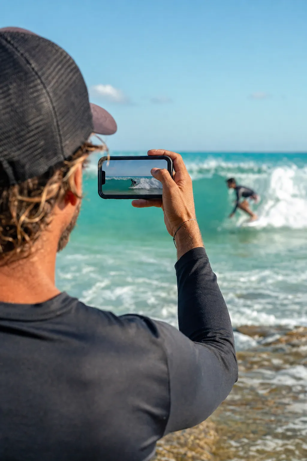 Pessoa filmando uma aula de surf na praia.